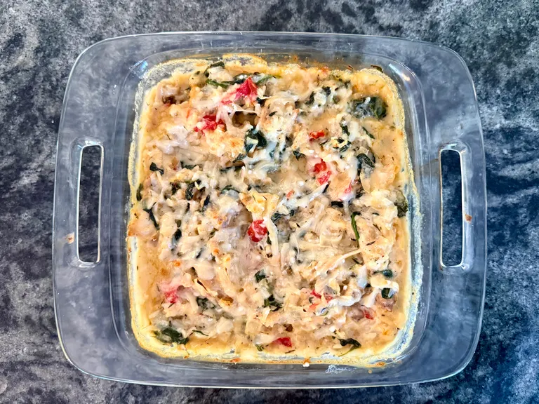 Creamy baked chicken, rice, spinach, and cottage cheese casserole topped with melted Parmesan cheese, a high-protein freezer meal perfect for postpartum recovery and healthy family dinners.