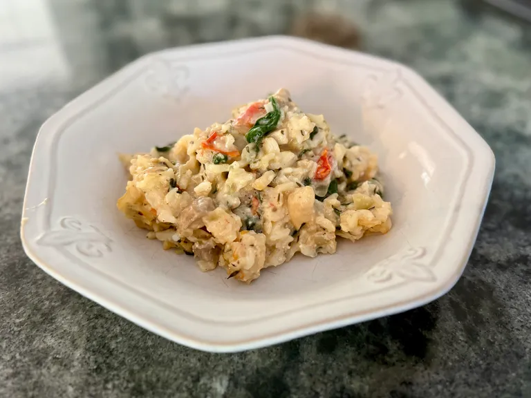 Creamy chicken, rice, spinach, and cottage cheese casserole served in a white bowl, a high-protein freezer meal perfect for postpartum recovery, meal prep, and healthy family dinners.