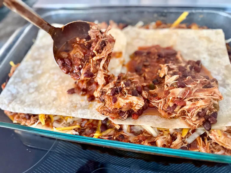 Layered high protein chicken enchilada casserole with tortillas and cheese