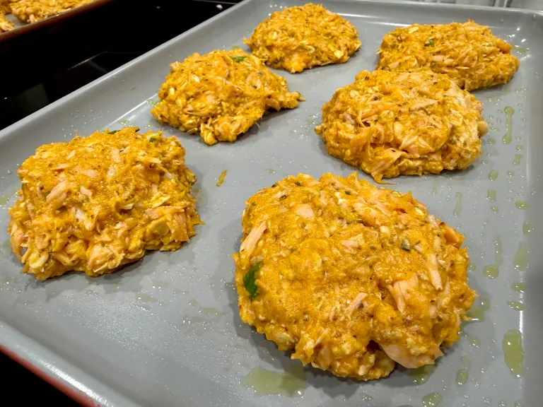 Homemade salmon sweet potato cake patties formed on a baking sheet before baking for a healthy high-protein dinner.
