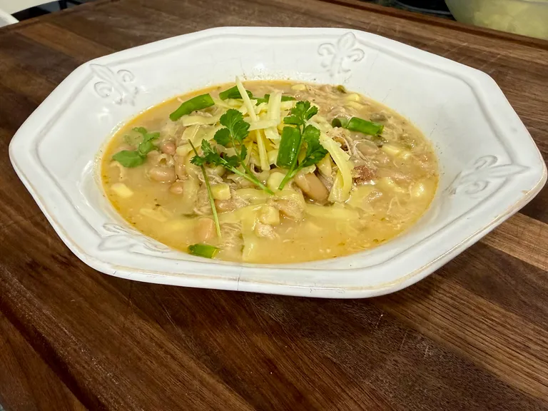 Protein packed creamy white chicken chili with shredded chicken, white beans, cheese, green onions, and cilantro, perfect for postpartum freezer meal prep and healthy family dinners.