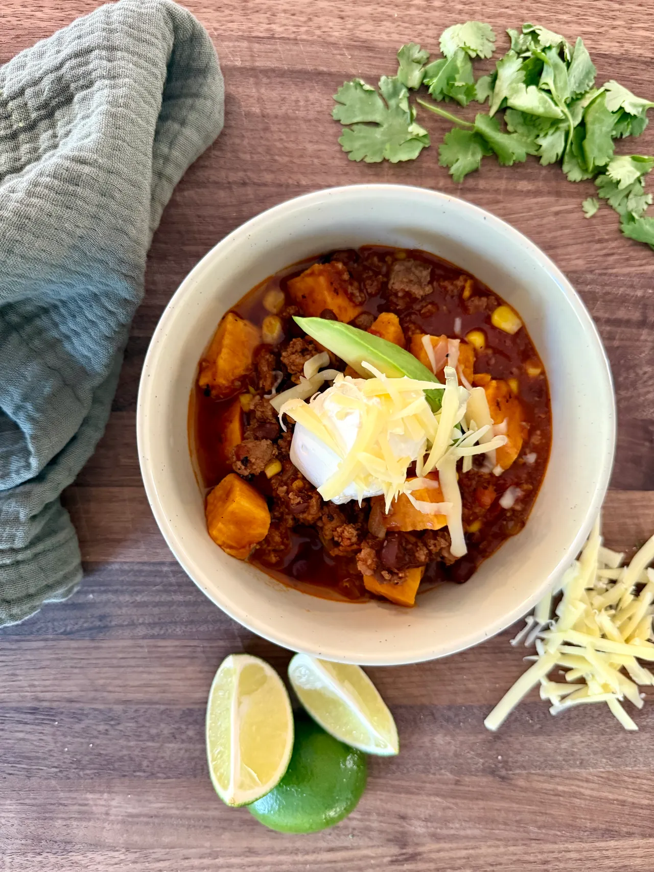 Healthy postpartum beef and sweet potato chili with black beans, corn, and lean ground beef topped with sour cream, cheddar cheese, and avocado
